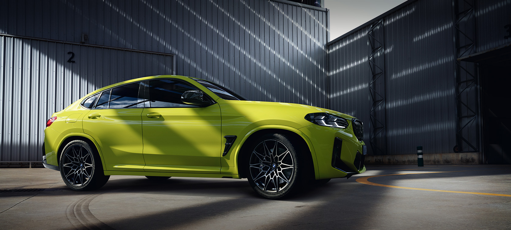 Imagine din partea laterală a unui BMW X4 M Competition F98 Facelift 2021 Galben Sao Paulo într-o hală