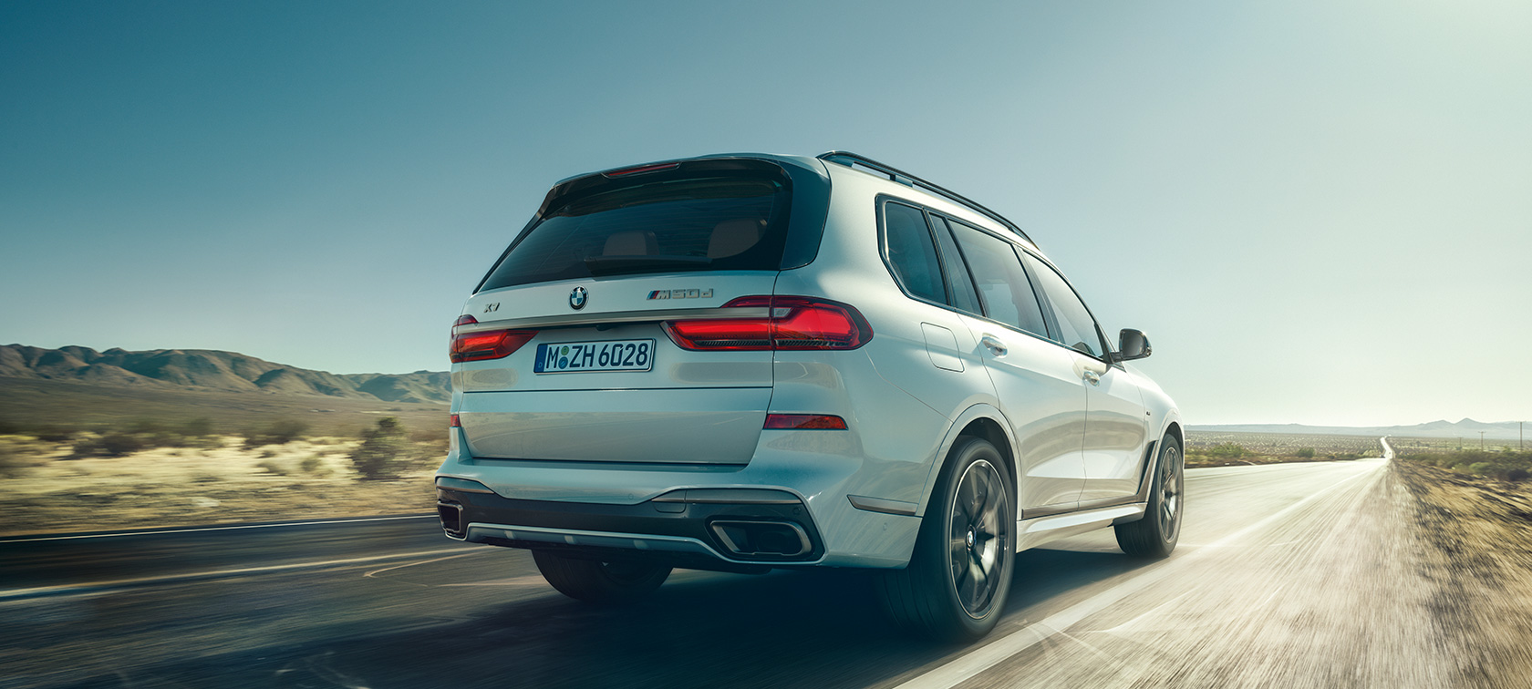 Imagine din spate cu BMW X7 M50d Imagine din spate cu BMW X7 M50d în Alb Mineral rulând pe o autostradă liberă, G07, 2019