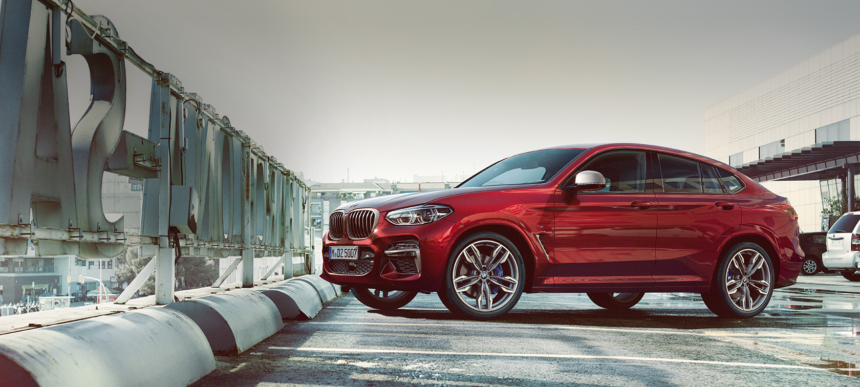 Imagine din lateral cu BMW X4 parcând Imagine cu partea laterală a BMW X4 M40i, G02, 2018, în Roşu Flamenco Brilliant Effect, parcând într-un garaj