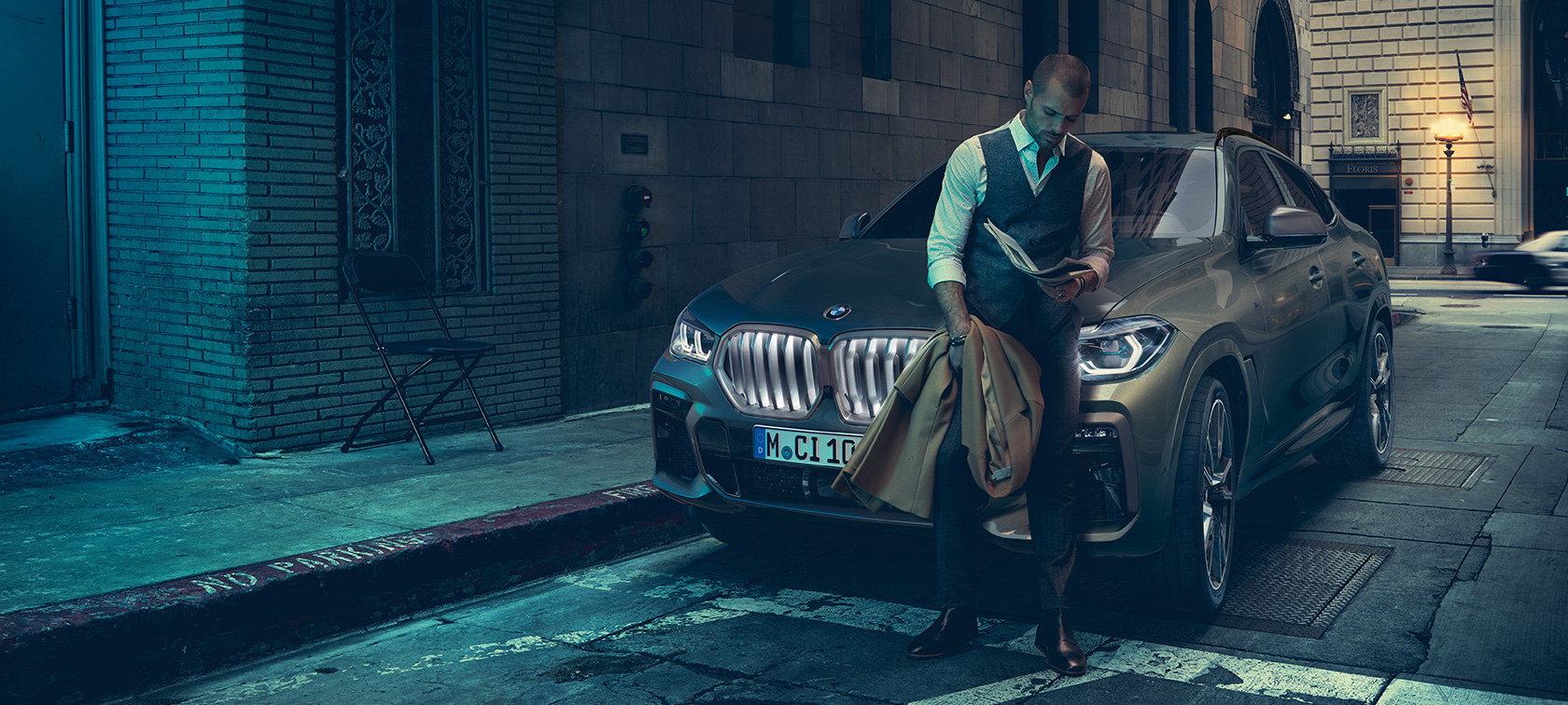 Un bărbat care se sprijină de BMW X6. Imagine din lateral cu un bărbat care se sprijină de BMW X6 într-un mediu urban.