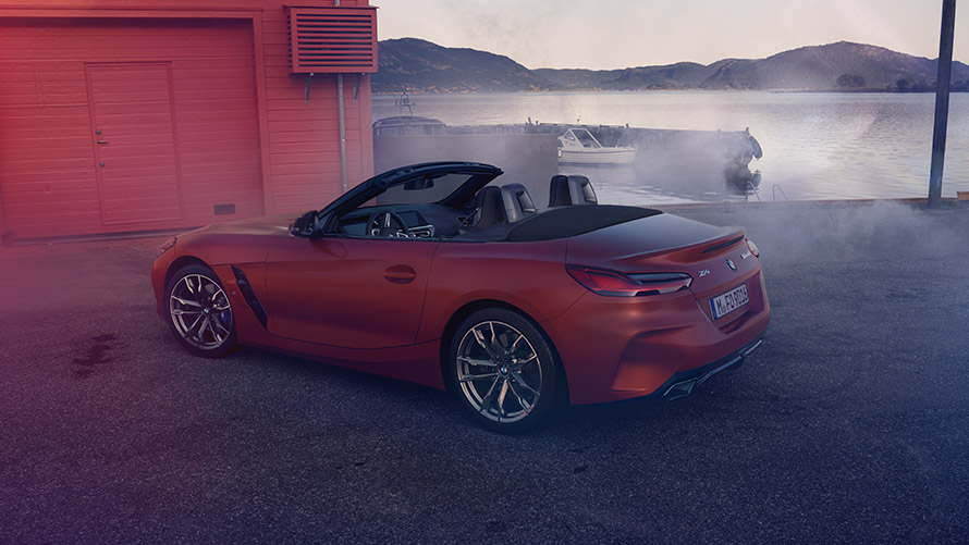 Perspectivă din spate asupra BMW Z4 „First Edition” portocaliu Perspectivă din spate asupra BMW Z4 „First Edition” portocaliu în faţa unei case roşii pe ţărm
