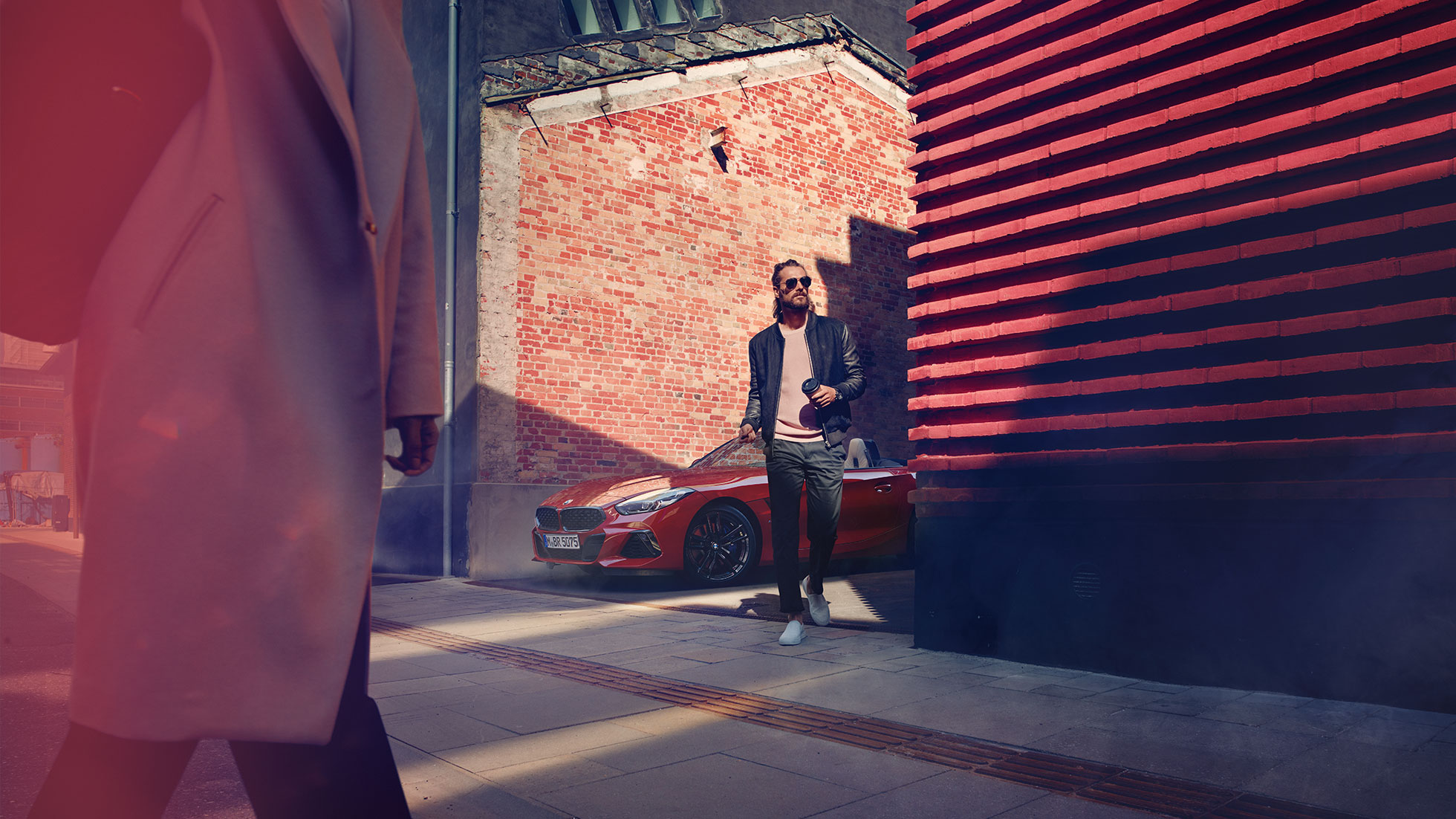 BMW Z4 Roadster pe o stradă laterală Un bărbat pe o stradă laterală în faţa unui BMW Z4 Roadster