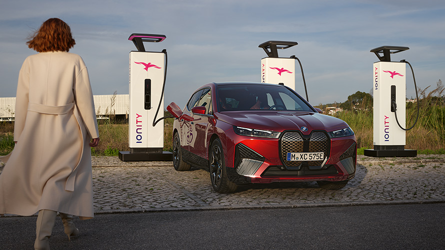 Vânzări speciale BMW Hub de sustenabilitate Prezentare generală BMW Charging Automobil BMW la o staţie de încărcare cu o femeie în prim-plan