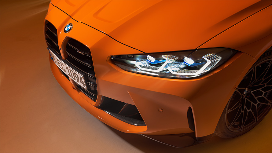 Imagine cu trei sferturi din partea frontală a BMW M4 Competition Coupé G82 2021, BMW Individual Portocaliu Fire staţionând, prim plan cu perspectivă de sus