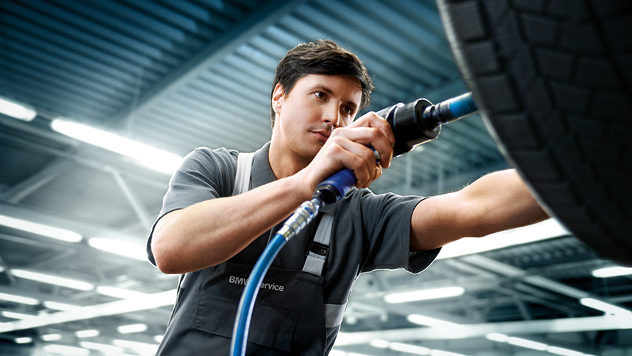 Service BMW pentru roţi, oferte BMW Imagine cu un specialist în service BMW reparând o roată BMW, oferte de vară BMW