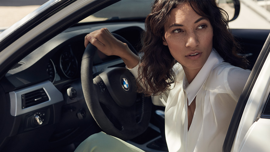 BMW Value Service Un client de service BMW priveşte prin portiera deschisă a automobilului său BMW